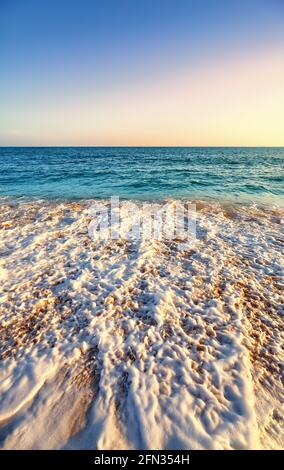 Sunset over the ocean with cloudless sky seen from a beach. Stock Photo