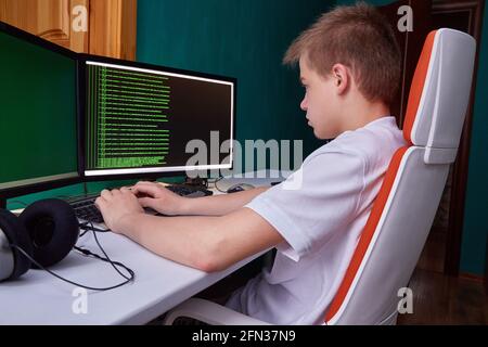 A young programmer guy prints the program code on the computer monitor screen. The concept of computer security, technology development and young prof Stock Photo
