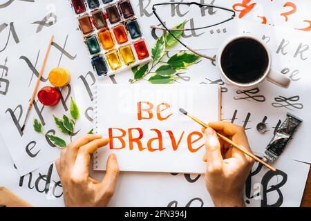 Overhead view on male man hands calligraphy sheets, nibs, paper, ink red pens.craft, hobby. Lettering workshop.flat lay motivational letters words quo Stock Photo