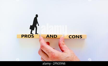 Pros and cons symbol. Wooden blocks with words 'Pros and cons'. Beautiful white background, businessman hand, businessman icon. Business, pros and con Stock Photo