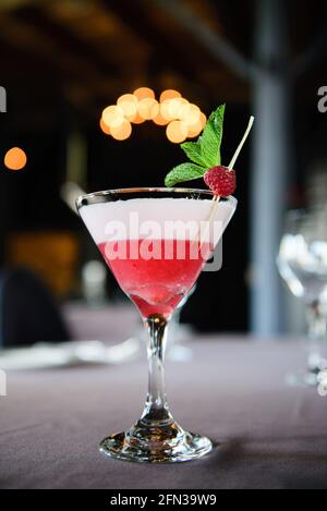 Classic clover club cocktail with raspberry and mint leaf from low angle with lights in bokeh Stock Photo