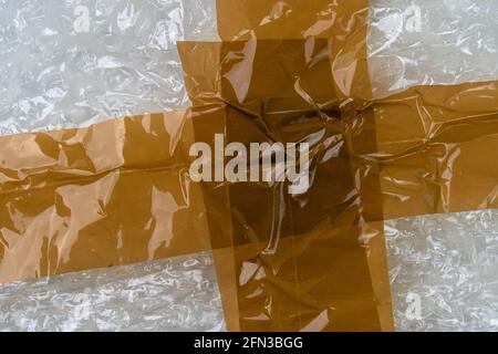 Adhesive tape on a bubble wrap. Wrinkled Abstract plastic background. Delivery concept. Macro Stock Photo