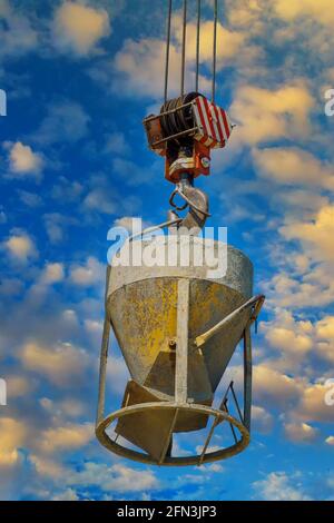 Working at height equipment with bucket liquid concrete container with hanging on crane hook in construction site building industry Stock Photo