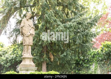 Monument in the garden of Brno Castle. Stone monument to a man on the background of spring trees. Stock Photo