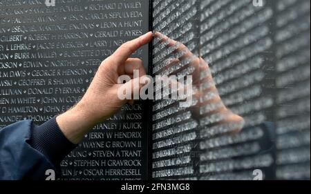 Tunkhannock, United States. 13th May, 2021. A man touches the Wall that Heals while looking for a name near the apex of the memorial.The Wall That Heals is a three-quarter scale replica of the Vietnam Veterans Memorial in Washington, DC, the wall travels around the country and is set up and displayed for 24 hours a day while it is in place. Credit: SOPA Images Limited/Alamy Live News Stock Photo