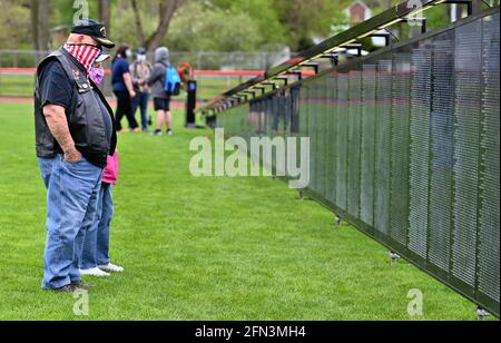 Tunkhannock, United States. 13th May, 2021. A veteran wearing a flag pattern mask looks at the Wall That Heals, a replica of the National Vietnam war memorial.The Wall That Heals is a three-quarter scale replica of the Vietnam Veterans Memorial in Washington, DC, the wall travels around the country and is set up and displayed for 24 hours a day while it is in place. Credit: SOPA Images Limited/Alamy Live News Stock Photo