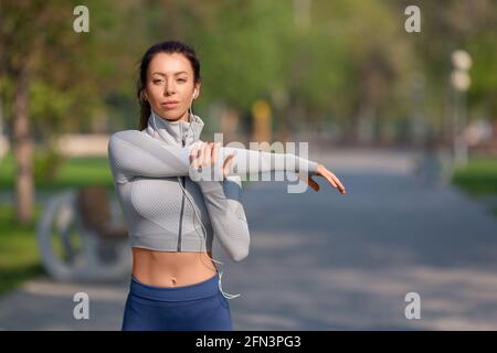 Women stretching shoulders for warming up before running or working out. Young female runner stretching arms before running at morning. Fitness and he Stock Photo