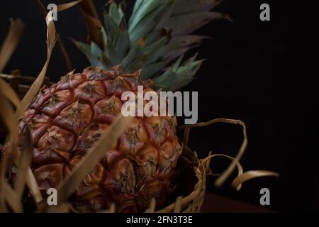 pineapple in a basket on a black table with a black background Stock Photo