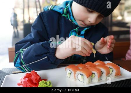 Child squeezes lemon juice on sushi in restaurant Stock Photo