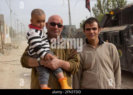 A group of civilians pose for a picture during the early days of the Mosul Operation in Al Bakir district of East Mosul, Iraq. Stock Photo