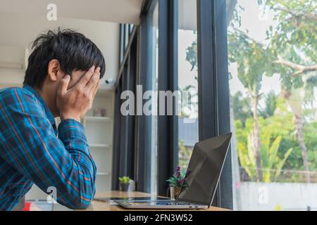 A frustrated young man alone during the covid-19 coronavirus pandemic induces credit card debt because of the poor economy and makes it impossible to Stock Photo