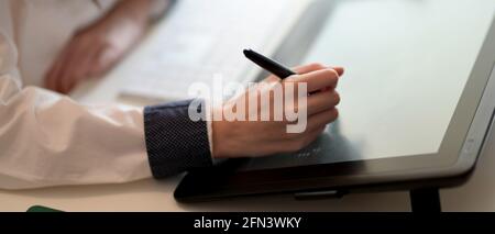 Close-up view of young woman drawing on Digital tablet in her workspace Stock Photo