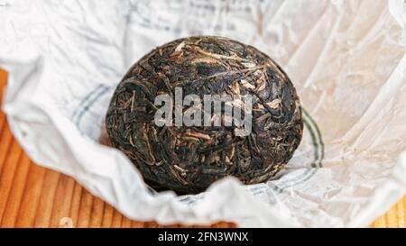 Chinese Raw Pu Er tea in the form of a nest in a paper wrapper Stock Photo