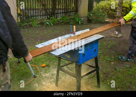 Two men cutting plank for terrace. Construction work in the yard. Stock Photo