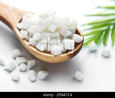 Dried sweet coconut cubes  in spoon  on white background. Stock Photo