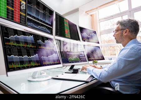 Stock Exchange Analyst Using Multiple Computer Screens Stock Photo