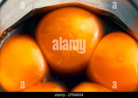 Bright egg yolks in a Japanese marinade in a glass.  Stock Photo
