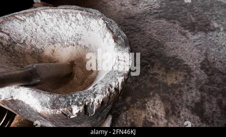 Ancient flour mortar. Wooden vessel for manual hand grinding. Authentic craft workshop. This method has been in use for many thousand years. Stock Photo