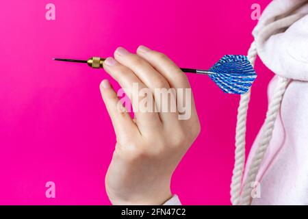 Darts game. Hand holds a dart. The process of throwing a dart. Stock Photo