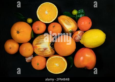 Orange fruits with leaves on a black background. Top view. Stock Photo