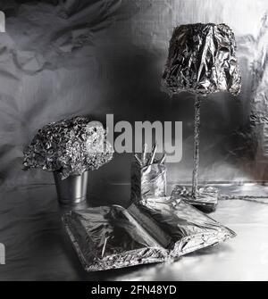 A lamp, a book and a plant pot wrapped in aluminum foil Stock Photo