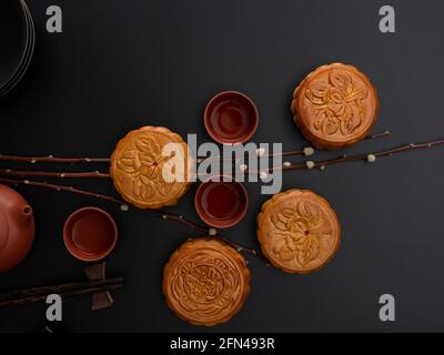 Top view of traditional moon cakes and tea cups on black table with copy space and decoration Stock Photo
