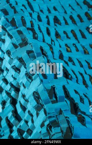 Industrially shredded cardboard packaging in blue light. For recycling waste materials, eco-friendly packaging, abstract shapes, shredding evidence. Stock Photo