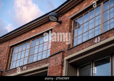 Helsinki / Finland - MAY 13, 2021: A close-up detail of an old red brick building with retro-style small windows. A metallic lamppost. Stock Photo