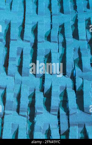 Industrially shredded cardboard packaging in blue light. For recycling waste materials, eco-friendly packaging, abstract shapes, shredding evidence. Stock Photo