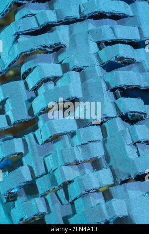 Industrially shredded cardboard packaging in blue light. For recycling waste materials, eco-friendly packaging, abstract shapes, shredding evidence. Stock Photo