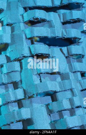 Industrially shredded cardboard packaging in blue light. For recycling waste materials, eco-friendly packaging, abstract shapes, shredding evidence. Stock Photo