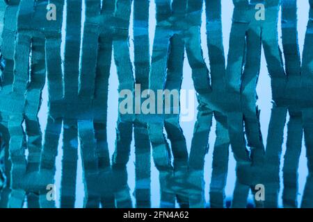 Industrially shredded cardboard packaging in blue light. For recycling waste materials, eco-friendly packaging, abstract shapes, shredding evidence. Stock Photo