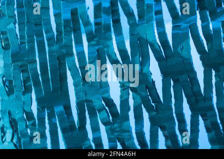 Industrially shredded cardboard packaging in blue light. For recycling waste materials, eco-friendly packaging, abstract shapes, shredding evidence. Stock Photo