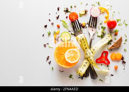 vegetables on forks with measuring tape on a white background with place for text. concept diet, weight loss, fat loss Stock Photo