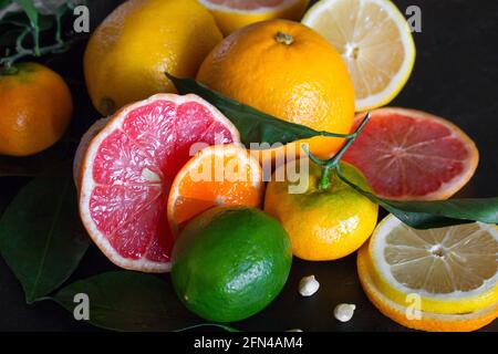 fresh citrus fruits orange, mandarin, lime, grapefruit, lemon and green leaves on a black background close-up Stock Photo