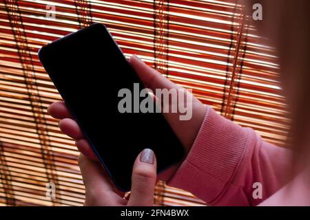 girl holds smartphone in hands, blank black screen with place for text mockup Stock Photo