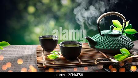 Asian tea set. Hot tea in pot and teacups. Japanese teapot and cups on  bamboo mat Stock Photo - Alamy