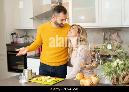 Happy couple in the kitchen. Romantic young couple preparing fresh fruit and coffee. Healthy life and love. Smiling people living together. Stock Photo