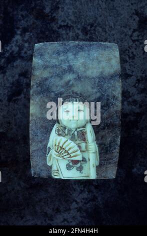 Carved and painted soapstone model of Japanese geisha girl on grey marble Stock Photo