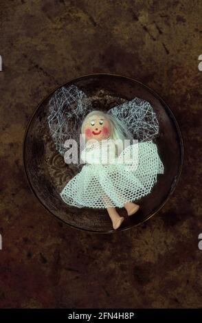 Model of fairy with cheeky face and gauze dress lying in brass dish Stock Photo