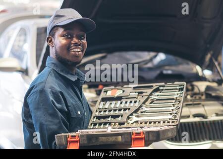 African maintenance male holding a set of car repair tools in box Stock Photo