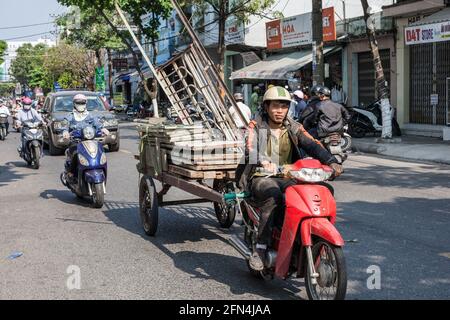 Vietnamese motorbike driver pulls wagon overloaded with building materials, Da Nang, Vietnam Stock Photo