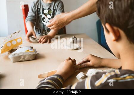 child playing with clay at home during quarantine. focused boy creating shapes with hands and using creativity and manual skills to mold toy shapes Stock Photo