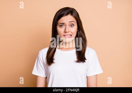 Photo portrait of worried nervous young woman biting lip worried in casual clothes isolated pastel beige color background Stock Photo