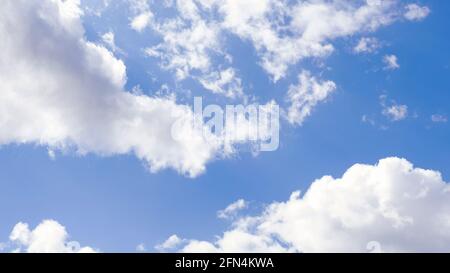 blue sky with white clouds backlit by sunlight. Fluffy cumulus clouds float across the clear sky Stock Photo