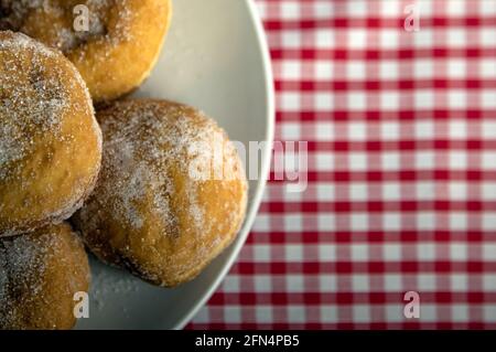 Top down view of Jam Donuts on a plate with a red gingham background and copy space Stock Photo
