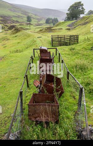 Old mining trucks rusting away at the entrance to an old historic lead mine at Wanlockhead in Scotland. Stock Photo