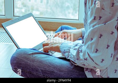 Young man working with laptop sitting near panoramic windows Stock Photo