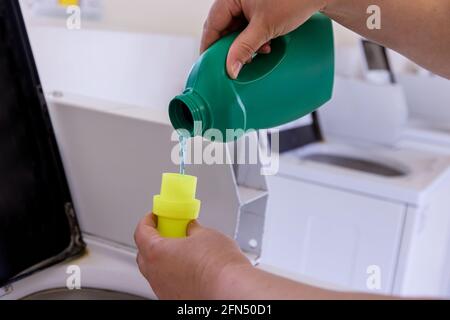 Woman pouring washing powder into the washing machine tank with laundry room Stock Photo