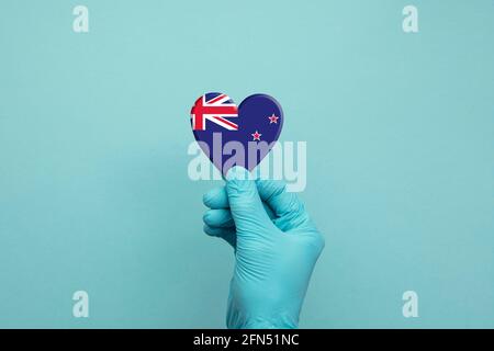 Hands wearing protective surgical gloves holding New Zealand flag heart Stock Photo